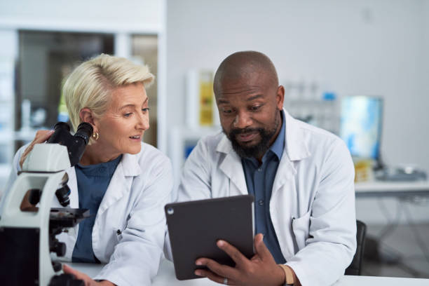 istock Scientist team, medical research and tablet with doctors discussing information technology, analysis or results in a science lab. Teamwork man and woman in a laboratory for innovation and development 1432720121
