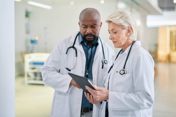 istock Tablet, diversity and doctors planning surgery and in conversation about medical tests results in hospital in New York. Teamwork, collaboration and black man talking to healthcare worker about report 1432720143