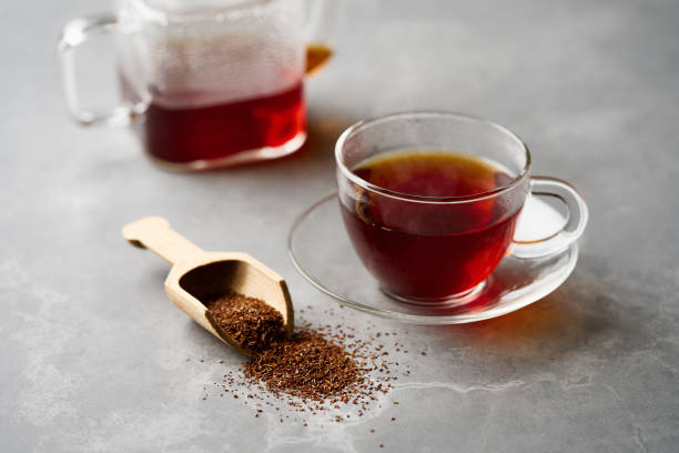 chá de rooibos quente em uma xícara e folhas de chá. - rooibos tea red indoors still life - fotografias e filmes do acervo