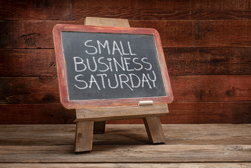 Small Business Saturday sign - white chalk handwriting on a blackboard against rustic barn wood - holiday shopping concept