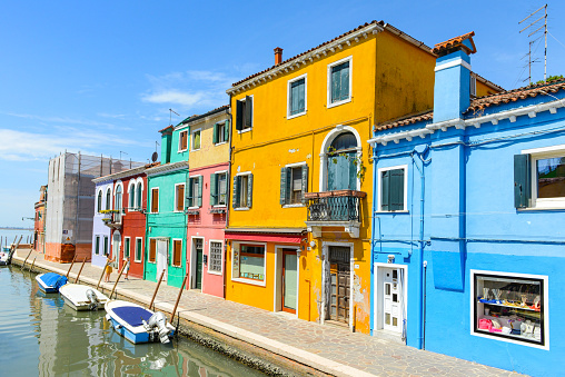 Burano Island, Venice, Italy - July 4, 2022: Tourists and Colorful houses on the canal in Burano island, Venice, Italy. Famous travel destination.