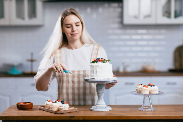 istock Pastry chef confectioner young caucasian woman with cake on kitchen table. 1432734556