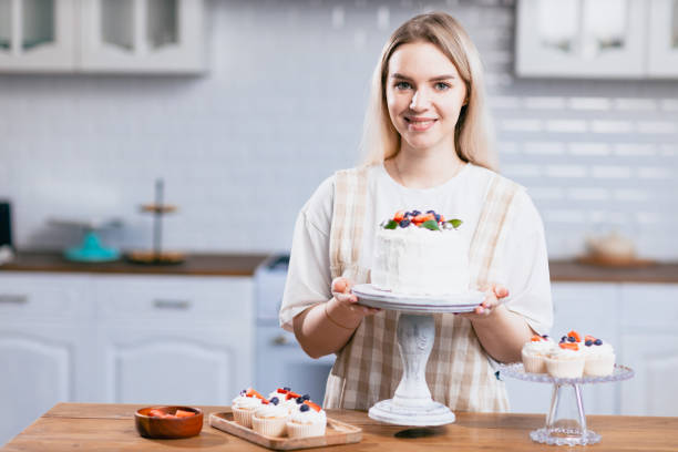 istock Pastry chef confectioner young caucasian woman with cake on kitchen table. 1432734561