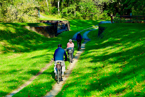 Oldtown, Maryland, USA - October 8, 2022: Bicyclists travel along the  Chesapeake and Ohio Canal National Historical Park towpath at Town Creek Aqueduct near the Potomac River.