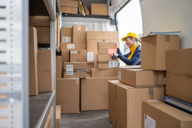 istock Postal worker scanning order package bar code, side view inside of delivery truck 1432735216