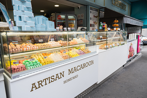 Paris, France - August 26 2022: Macaron shop in the streets of Paris. Assortment of different flavours of almond cookies, sandwiches, crepes.