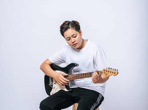 Girl sitting on a chair and playing guitar.