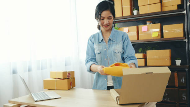 Fashion designer Women packing box on table checking goods quality package. Asian women startup small business at home office desk pack fashion design clothing. Asian woman packing startup business diseñadora de moda mujer caja de embalaje en la mesa comprobando la calidad del paquete de productos. mujeres asiáticas que inician pequeñas empresas en el escritorio de la oficina en casa paquete de ropa de diseño de moda. empresa de embalaje de mujer