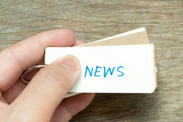 Photo of Man hold the flash card with handwriting word news on wood background