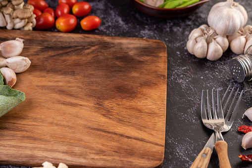 Garlic, tomato, cutting board, and cooking fork. Selective focus