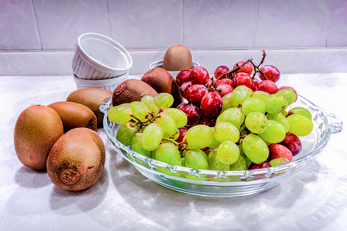 Summer fruits are arranged in a glass bowl in the kitchen.