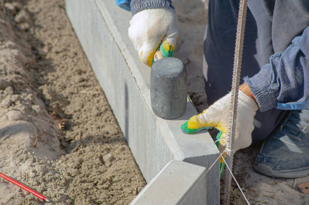 istock Workers using machine to align and set the concrete curbs. Concrete kerb installation at sidewalk edging. 1432761744