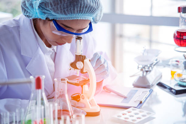 istock Asian Woman scientist hand write note research in medical lab look at science microscope medical test. Researcher biology chemistry. Asian Female technician laboratory using microscope blood test 1432764777