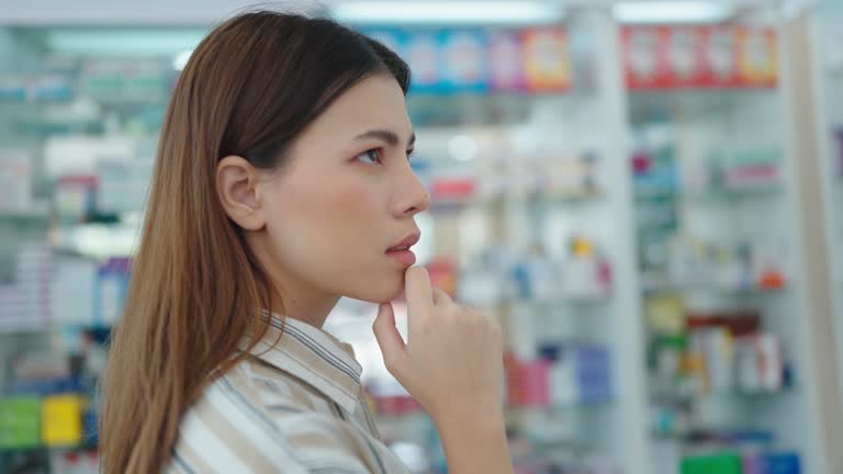 A woman customer standing and looking products medicines supplements at pharmacy