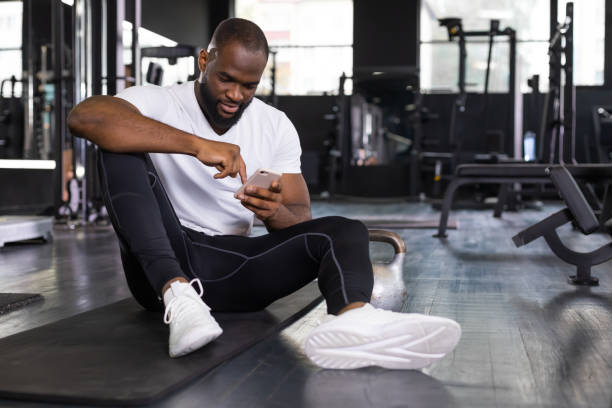 istock Sporty african man resting, looking at phone having break after doing exercise 1432767351