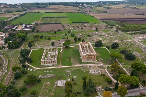 This photo is made with a drone. It shows the ancient Greek and roman temple of Neptune. The temple is located in the old city which is Paestum.