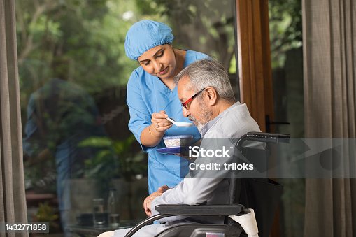 istock Caregiver feeding food to old man on wheelchair 1432771858