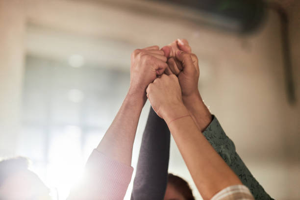 Raise your fists in unity! Close up of group of unrecognizable people raising their fists in success. punching the air stock pictures, royalty-free photos & images