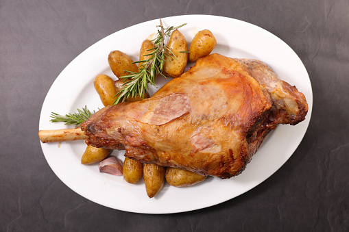 Roast leg of lamb with potatoes and rosemary on plate