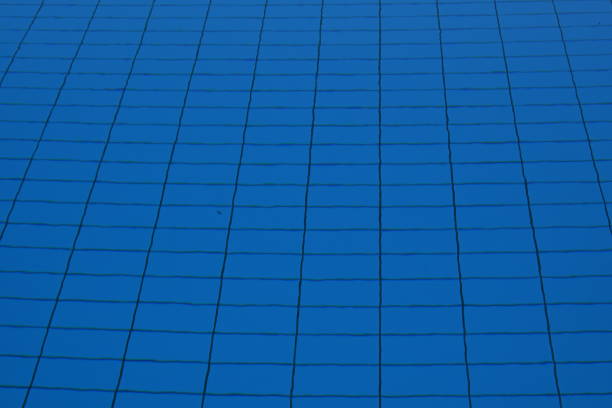 Rectangular tiles on the bottom of a swimming pool full of water in horizontal view. It is a cutout showing the structure  of the tiles. They are of blue color and defocused because of the water.