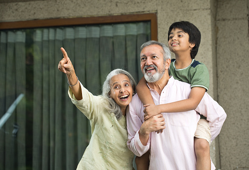 Carefree grandparents spending leisure time with grandson at home