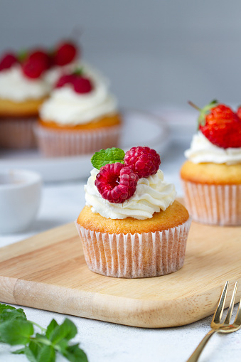 Cupcake with raspberries and mint on a wooden board, close-up