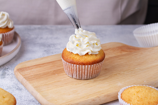Forming a cap of cream on a cupcake with a pastry bag, close-up. Part 7/9