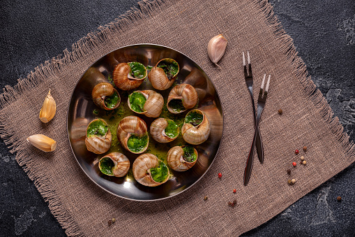 Bourgogne Escargot Snails with herb garlic oil in a metal plate.
