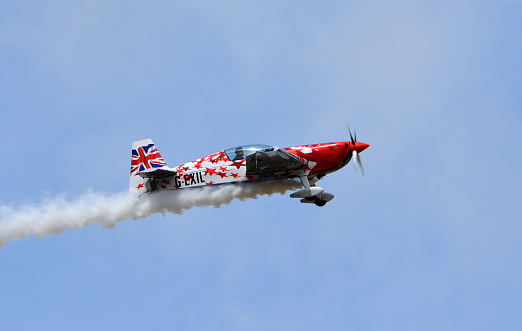Little Gransden, Cambridgeshire, England - August 28, 2022:   Global All Stars Extra 300S stunt aircraft in flight with smoke