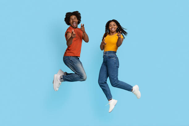 istock Carefree black lovers jumping up and pointing at camera 1432777821
