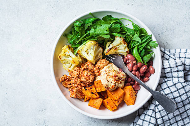 Winter vegan buddha bowl with tofu, beans, baked vegetables, hummus and beans. stock photo