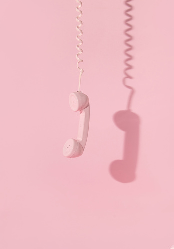 Creative layout with pink retro phone handset on pastel pink background. 80s or 90s retro fashion aesthetic telephone concept. Minimal romantic handset idea. Valentines day idea.