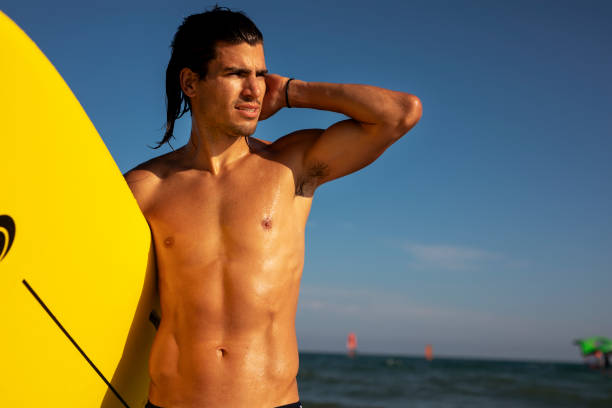 istock Young man with a surfboard on the beach. 1432780483