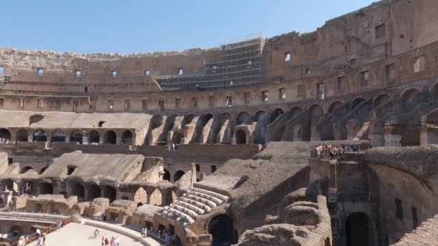 Panning shot inside of Famous Colosseum in Rome on Sunny day, oval amphitheatre ruins. Italy