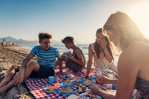 family having summer picnic breakfast on the beach - breakfast eating people teens imagens e fotografias de stock
