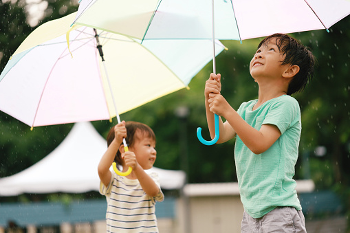 Portraits of cute little Asian boys playing with umbrella in the rain