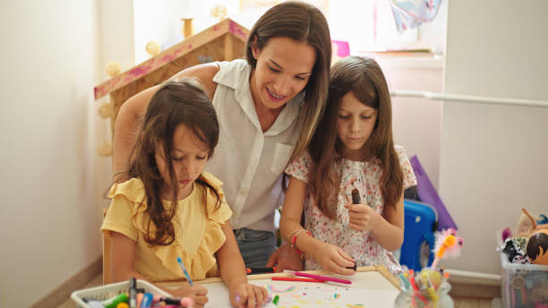 istock Smiling mother and two daughters drawing together at home 1432786185