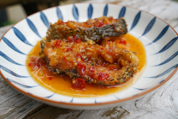 Fried fish with chilli in a ceramic plate on an old wooden floor. The taste is sour, sweet and slightly spicy.