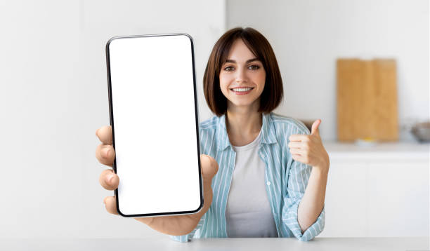istock New app. Cheerful lady showing smartphone with blank screen at kitchen interior, selective focus, mockup 1432790258