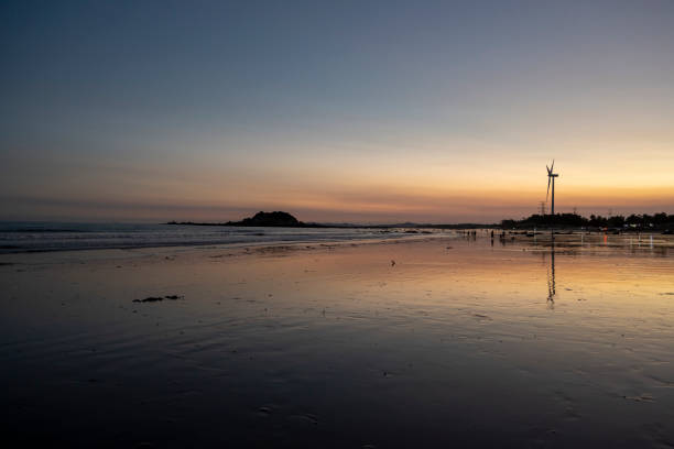 Empty seaside beach at evening in Fujian province, China. Wind turbines
