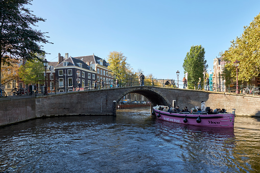 Open cruise boat at city canals of Amsterdam, The Netherlands.
