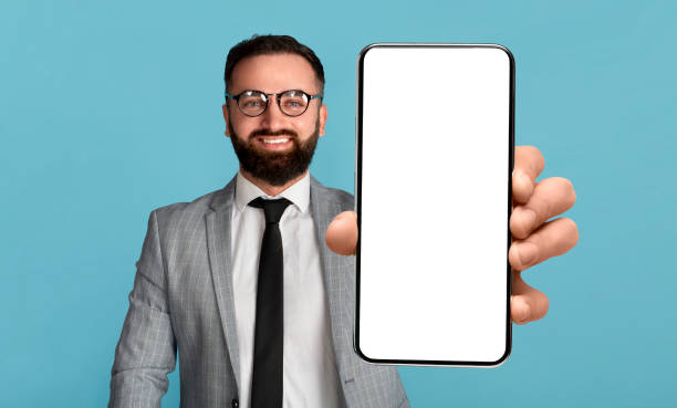 istock Mobile offer. Handsome businessman holding mobile phone with empty screen, showing device with mockup 1432790333