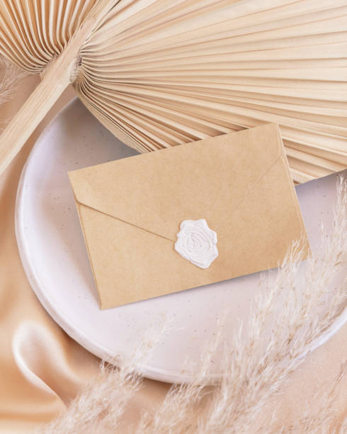 istock Sealed envelope on plate on dried palm leaf and beige silky fabric close up, mockup 1432795416
