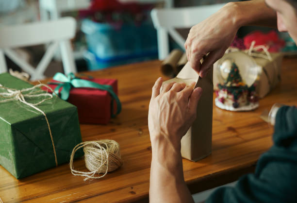 istock Man wrapping Christmas gift at home 1432801476