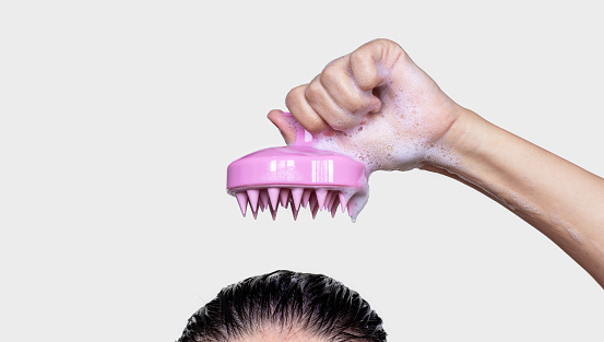 woman using silicone pink shampoo brush for scalp massage hair growth stimulation isolated