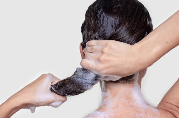 mujer que usa un cepillo de champú rosa de silicona para masajear el cuero cabelludo estimulación del crecimiento del cabello aislado - health spa women spa treatment massager fotografías e imágenes de stock
