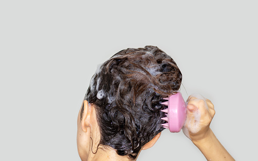 mujer que usa un cepillo de champú rosa de silicona para masajear el cuero cabelludo estimulación del crecimiento del cabello aislado photo