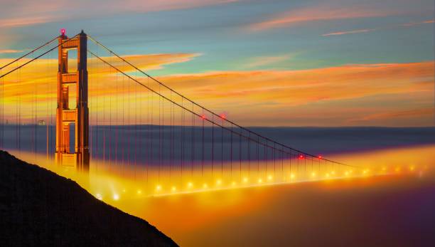 manhã nebulosa na golden gate bridge na califórnia com nuvens amarelas em um céu brilhante ao nascer do sol - golden gate bridge nature vacations fog - fotografias e filmes do acervo