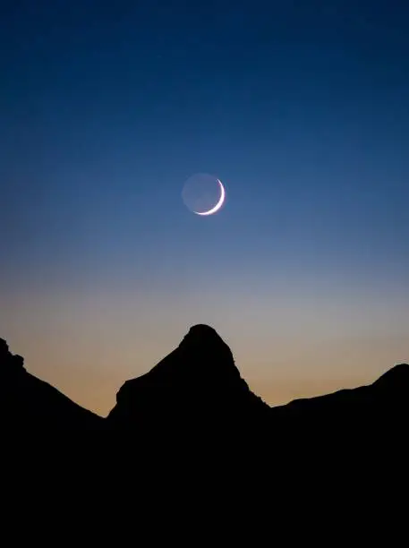 The waxing crescent moon over mountain silhouette