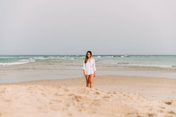 istock Happy woman standing on sandy beach 1432809932